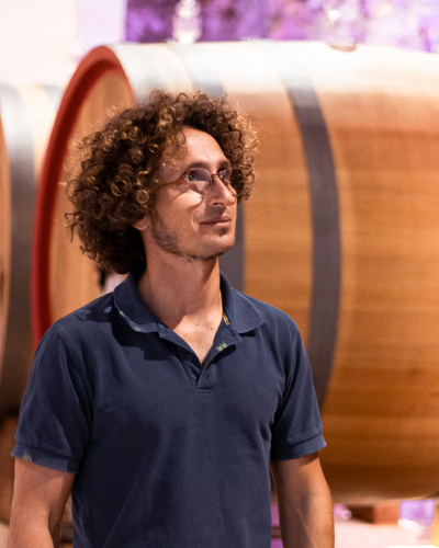 Giuseppe Capurso che guarda in alto a destra con allo sfondo una botte